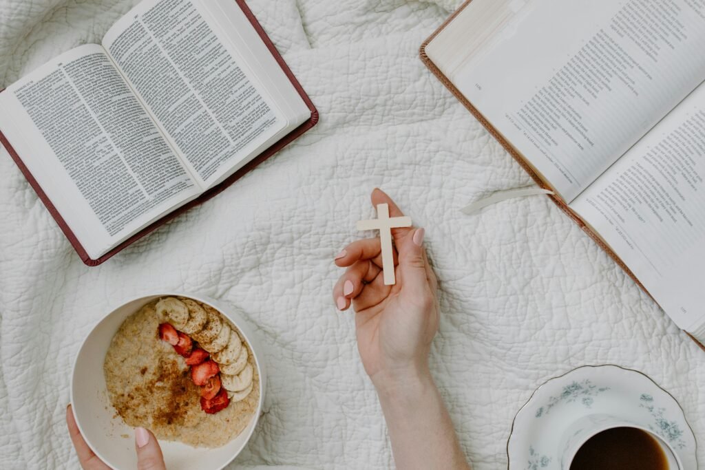 A serene morning setup with an open Bible, cross, and healthy breakfast on a cozy quilt.